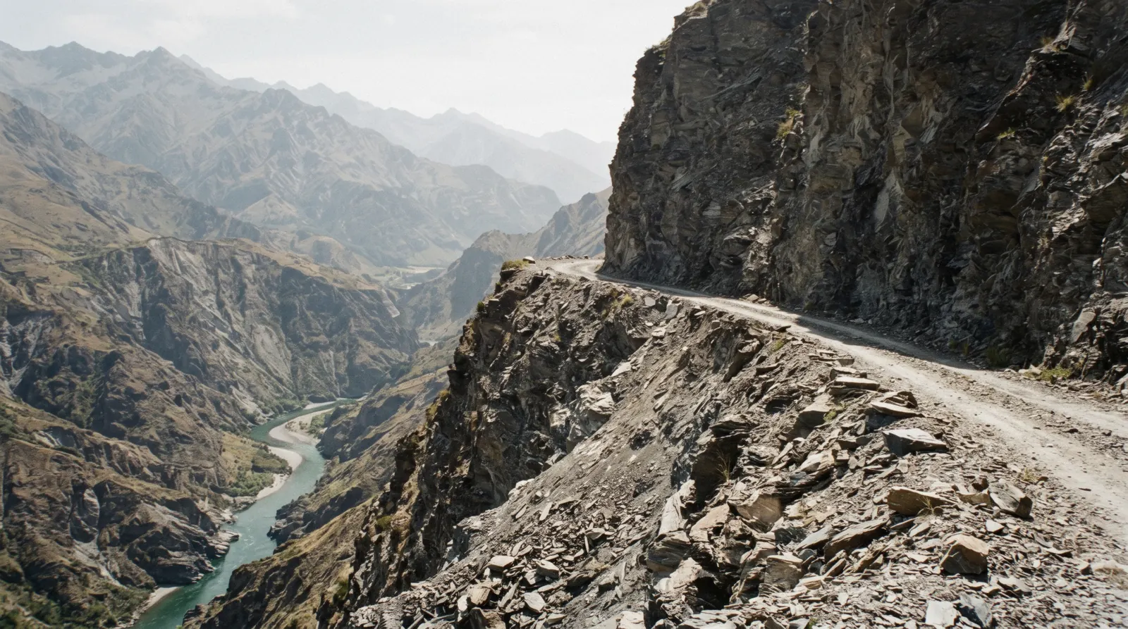 The single-lane gravel shelf of Skippers Canyon Road cut into a cliff high above the Shotover River, on a 4WD trip into Skippers Canyon from Queenstown
