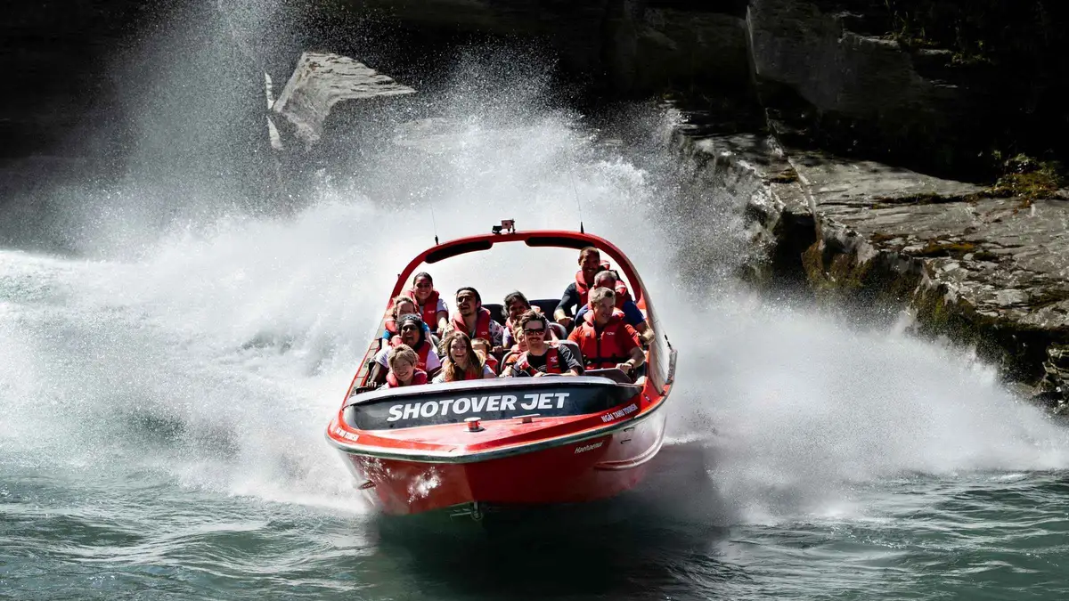 A jet boat spinning below the schist walls of the Shotover Canyon — Shotover Jet, Queenstown, New Zealand