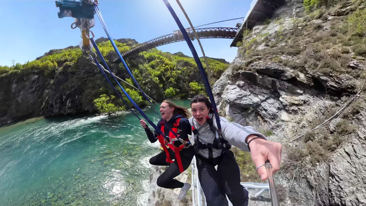 Two riders swinging out across the Kawarau Gorge — Kawarau Bridge bungy, Queenstown, New Zealand