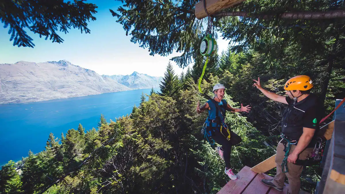 A guide lowering a rider on the 21-metre drop to the forest floor — Ziptrek Queenstown ziplining, New Zealand