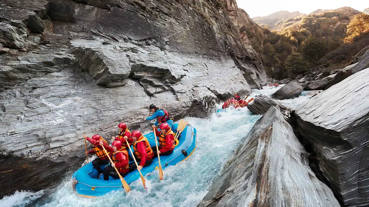 A raft dropping through whitewater on the Shotover River — Queenstown adventure activities, New Zealand