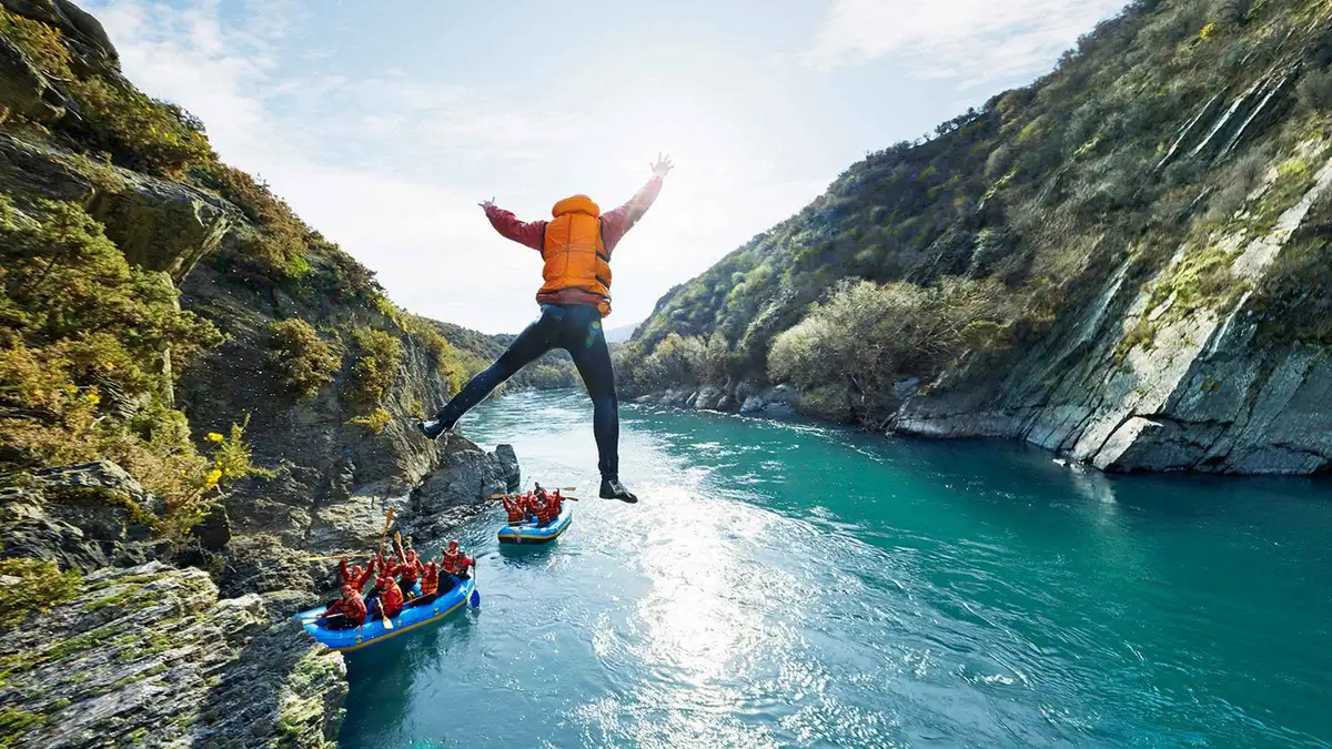 A raft team paddling a wide rapid on the Kawarau River — Queenstown adventure activities, New Zealand