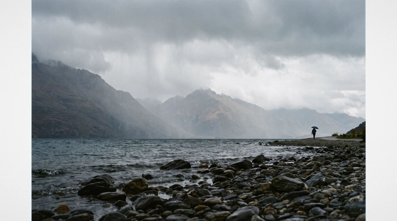A rain squall crossing Lake Wakatipu with the far range half erased by cloud, the Queenstown weather by month reality on a wet afternoon